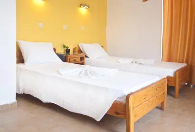 two beds in a room with white sheets at Omiros in Faliraki
