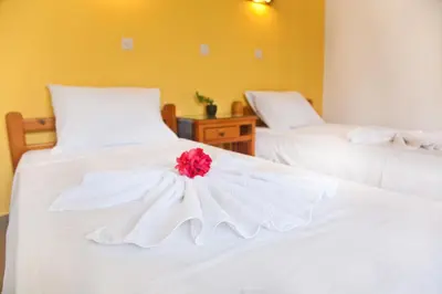 two beds with white sheets with a red flower on them at Omiros in Faliraki