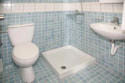 a blue tiled bathroom with a toilet and a sink at Omiros in Faliraki