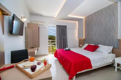 a hotel room with a bed with a red blanket at CasaStavris - Aparts & Pool Suites in Faliraki