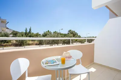 a small table and chairs on a balcony with a drink at CasaStavris - Aparts & Pool Suites in Faliraki