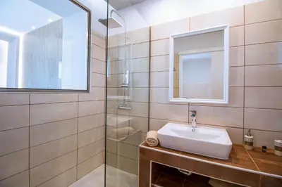 a bathroom with a sink and a mirror at CasaStavris - Aparts & Pool Suites in Faliraki