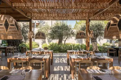 a restaurant with wooden tables and chairs and a large window at Lindos Aqua Terra in Líndos