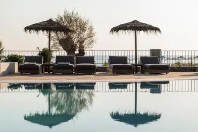 a group of chairs and umbrellas next to a pool at Lindos Aqua Terra in Líndos