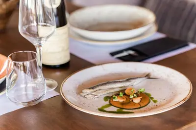 a plate of food on a table with a bottle of wine at Lindos Aqua Terra in Líndos