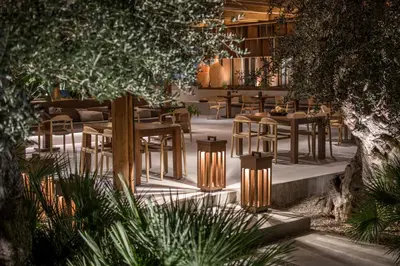 a restaurant with wooden tables and chairs and trees at Lindos Aqua Terra in Líndos