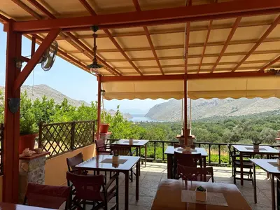 a restaurant with tables and chairs with mountains in the background at Taxiarchis in Symi