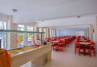 a dining room with red chairs and tables with food at Lito Hotel in Ixia
