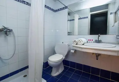 a white bathroom with a toilet and a sink at Lito Hotel in Ixia