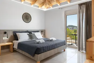 a bedroom with a bed and a large window at L & C Boutique Apartments in Kremasti