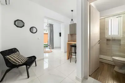 a white hallway with a chair and a bathroom at L & C Boutique Apartments in Kremasti