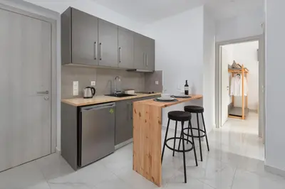 a kitchen with gray cabinets and bar stools at L & C Boutique Apartments in Kremasti