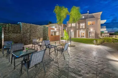 a patio with tables and chairs in front of a house at L & C Boutique Apartments in Kremasti