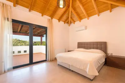 a bedroom with a bed and a large window at Seven Springs Villas Artemis Villa in Kolimbia