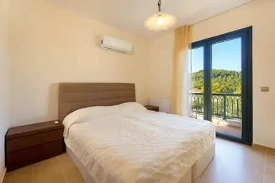 a bedroom with a bed and a large window at Seven Springs Villas Artemis Villa in Kolimbia