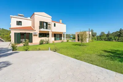 a house with a large yard with a grassy field at Seven Springs Villas Artemis Villa in Kolimbia