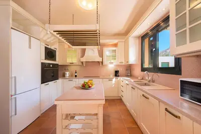 a kitchen with white cabinets and a bowl of fruit on the counter at Seven Springs Villas Artemis Villa in Kolimbia