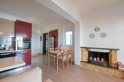a kitchen and dining room with a table and a fireplace at Aegiali Sea View Villa in Gennadi