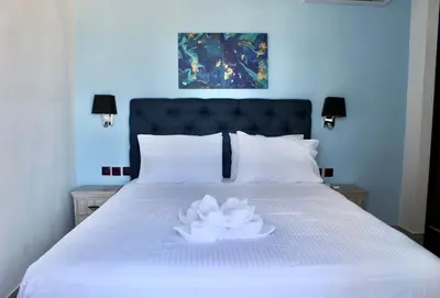a white flower on a white bed with two lamps at Aegiali Sea View Villa in Gennadi