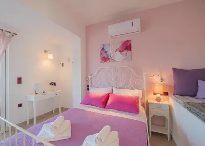 a bedroom with a bed with pink and purple sheets at Aegiali Sea View Villa in Gennadi