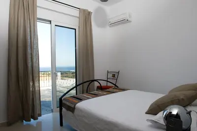 a bedroom with a bed with a view of the ocean at Villa Mamma Mia in Gennadi