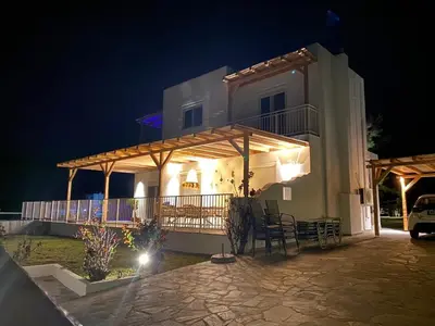 a large white building with a porch at night at Villa Mamma Mia in Gennadi