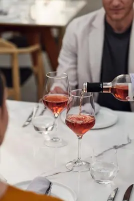 a person pouring wine into two wine glasses on a table at Casa Cabana Boutique Hotel & Spa - Adults Only in Faliraki