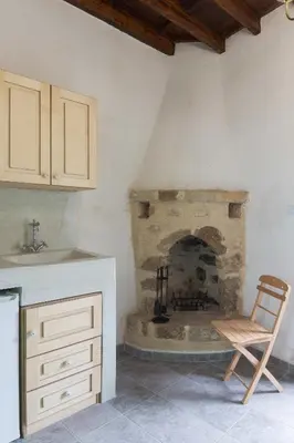 a kitchen with a stone fireplace with a chair at Hartso - Traditional loft, renovated former forge in Gennadi in Gennadi