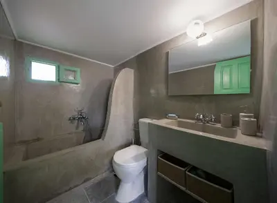 a bathroom with a sink and a toilet and a mirror at Hartso - Traditional loft, renovated former forge in Gennadi in Gennadi