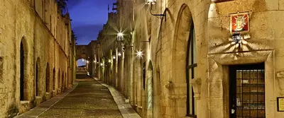 an alley between two stone buildings with street lights at Emerald Dream House in Rhodes Town
