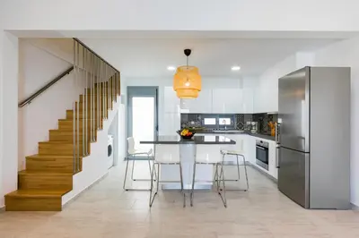 a kitchen with a dining room table and a staircase at Villa Serene with swimming pool in Lindos in Líndos