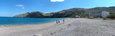 two people walking on a beach near the water at Villa Serene with swimming pool in Lindos in Líndos