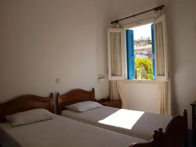 two beds in a bedroom with a window at Horio Village Rooms in Symi