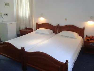 a bedroom with two beds with white sheets at Horio Village Rooms in Symi