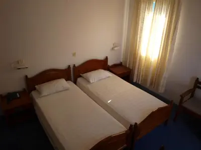 two twin beds in a room with a window at Horio Village Rooms in Symi