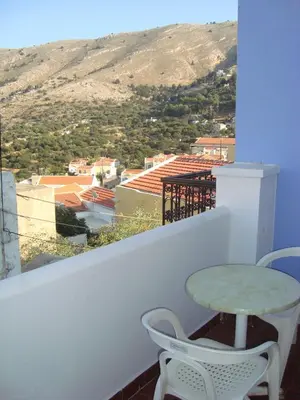 a table and chairs on a balcony with a view at Horio Village Rooms in Symi