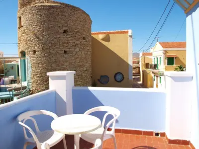 a patio with a table and chairs on a balcony at Horio Village Rooms in Symi