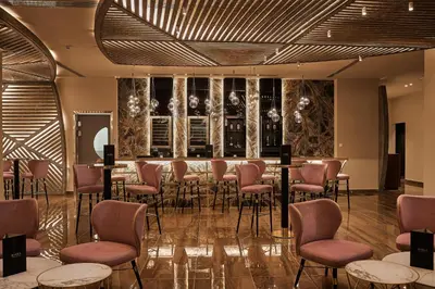 a restaurant with a bar with pink chairs and tables at Mayia Exclusive Resort & Spa - Adults Only in Kiotari