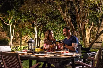 a man and woman sitting at a table with a bottle of wine at Lemuria Manor, Wine Dark Sea Villas in Rhodes Town