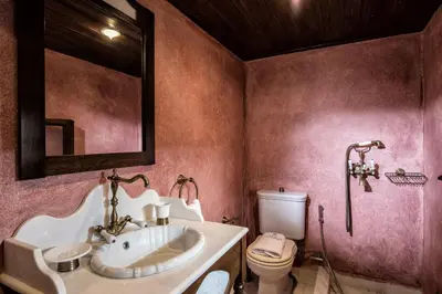 a bathroom with a sink and a toilet and a mirror at Lemuria Manor, Wine Dark Sea Villas in Rhodes Town