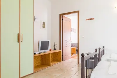 a bedroom with a door open to a bedroom with a television at Kaya Sea Apts - Stegna Beach in Archangelos