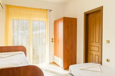 a bedroom with two beds and a window and a door at Kaya Sea Apts - Stegna Beach in Archangelos