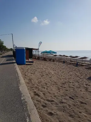 a beach with tables and umbrellas and the ocean at Sea Spirit in Afantou