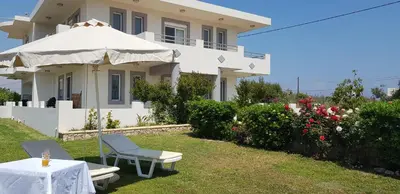 a white house with a table and an umbrella at Sea Spirit in Afantou