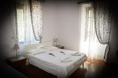 a bedroom with a bed with white sheets and windows at Nymph in Sálakos