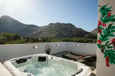 a hot tub on a balcony with mountains in the background at Stergios top view residence with jacuzzi in Kolimbia