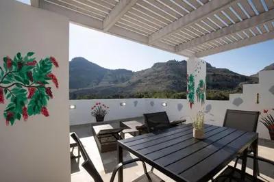 a dining room with a table and chairs on a balcony at Stergios top view residence with jacuzzi in Kolimbia