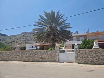 a palm tree behind a stone wall with a gate at Stergios top view residence with jacuzzi in Kolimbia