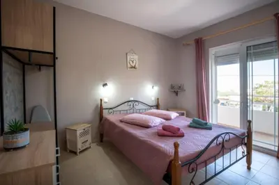 a bedroom with a bed with pink pillows and a window at Stergios top view residence with jacuzzi in Kolimbia