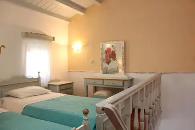a bedroom with two beds and a desk and a window at Dorian Hotel in Symi